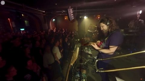 Menschen stehen vor der Bühne auf der eine Band spielt