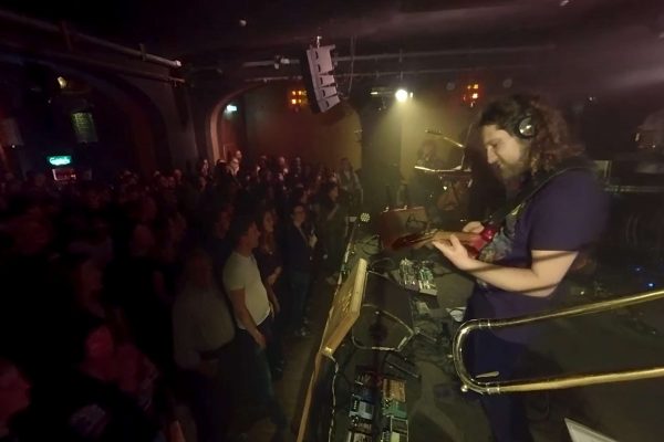 Menschen stehen vor der Bühne auf der eine Band spielt
