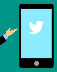 Eine Hand zeigt auf ein illustriertes Smartphone, auf dem das Twitter Logo zu sehen ist.